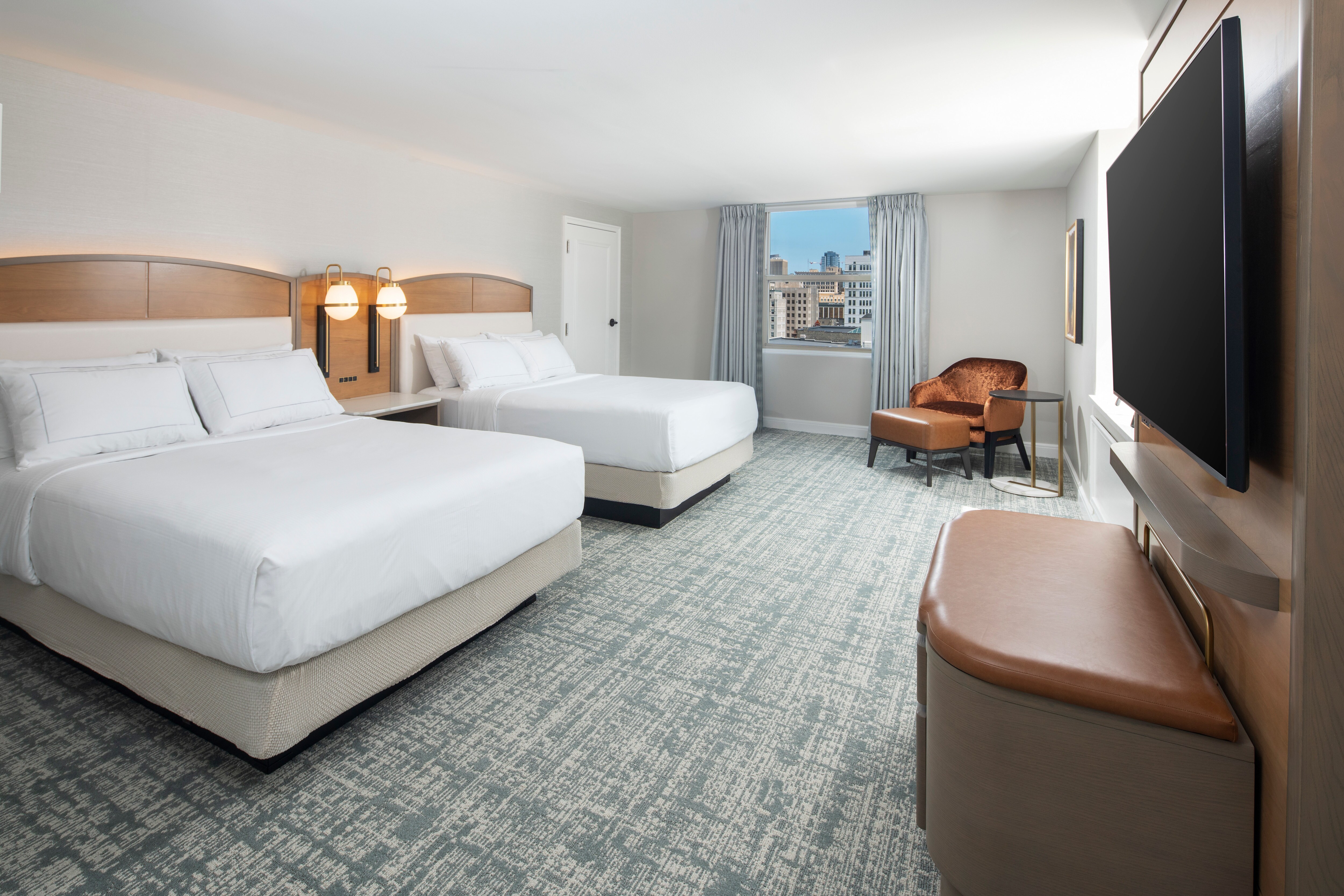The bedroom in the Plaza suite with two beds, a sitting area, and a window.